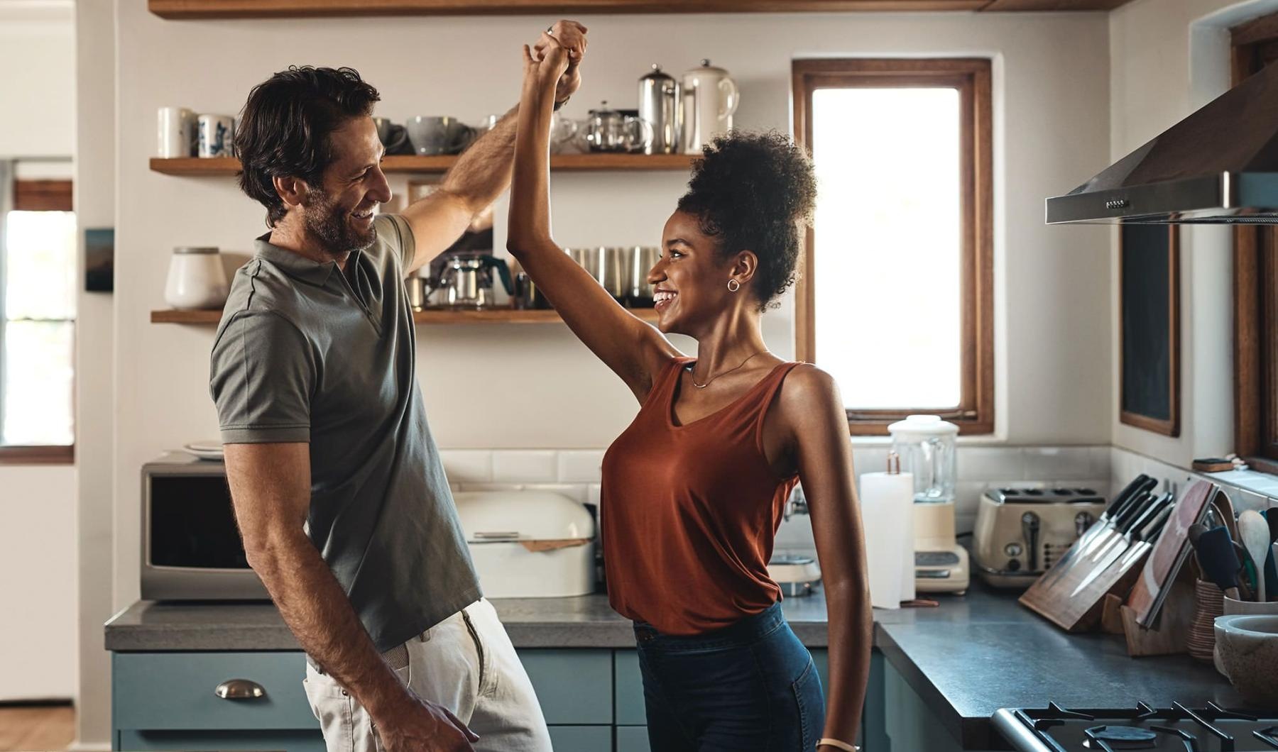 a man and a woman dance in well lit kitchen