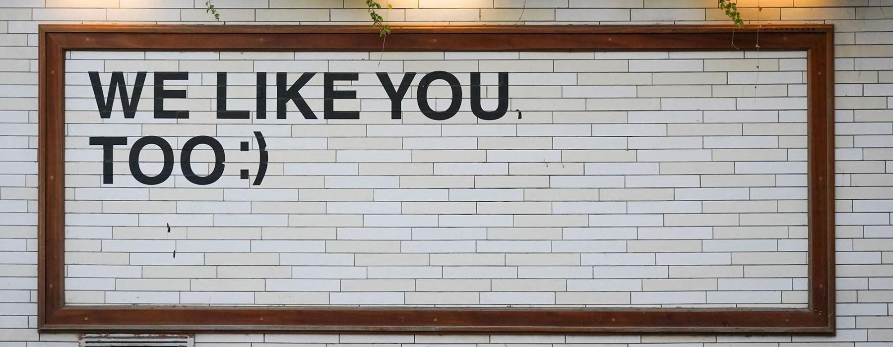 a sign on a tile wall that says, "We like you too"